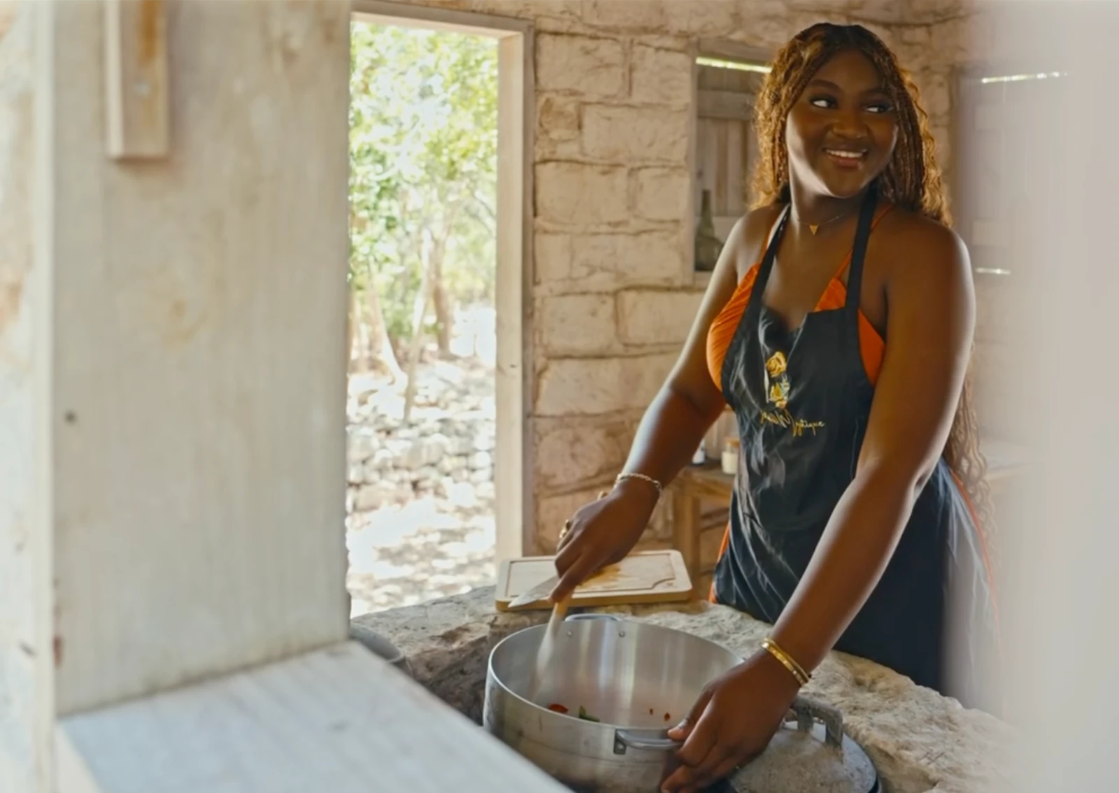 An Island Mystique host preparing a traditional meal in a warm stone kitchen