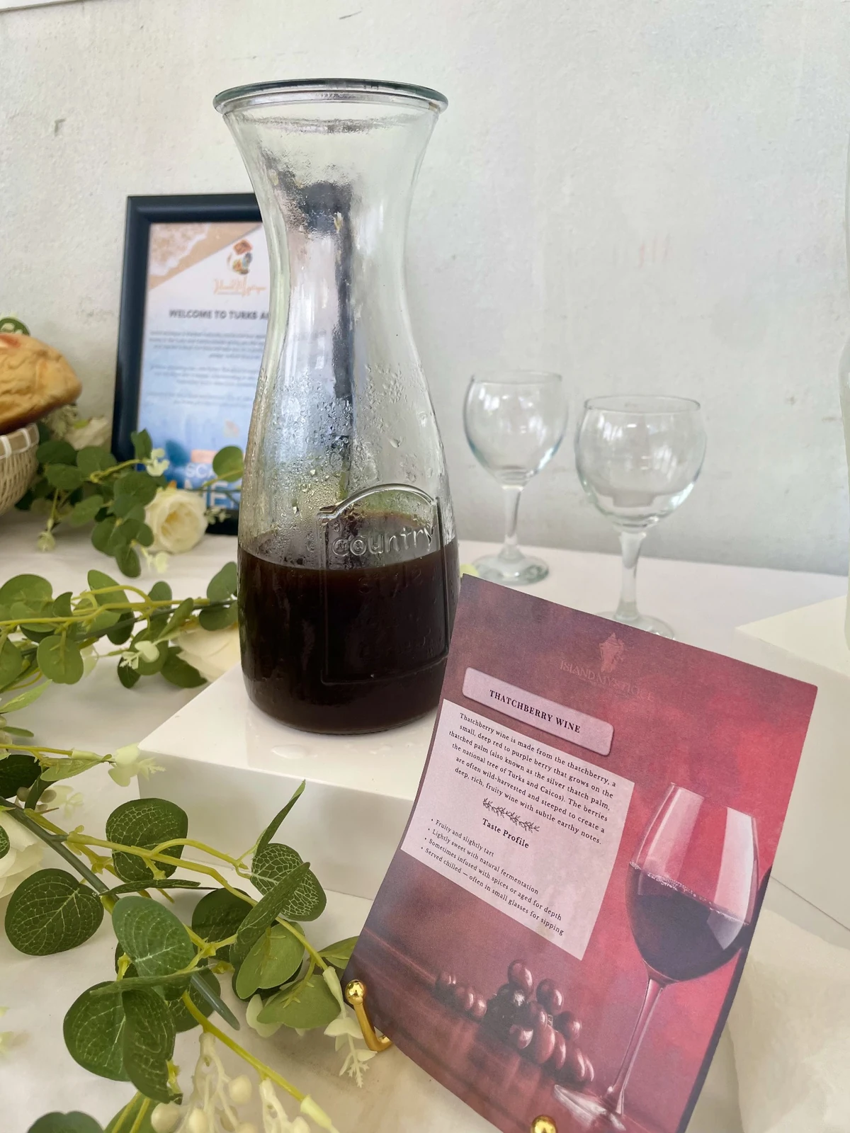 Local thatchberry wine displayed in a glass carafe beside Island Mystique table details
